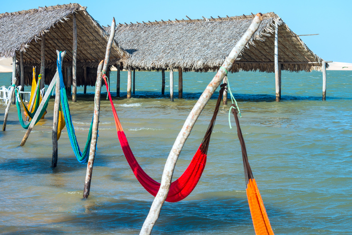 Na imagem vemos o mar de Jericoacoara em uma manha ensolarada, redes coloridas para os turistas deitarem no mar.